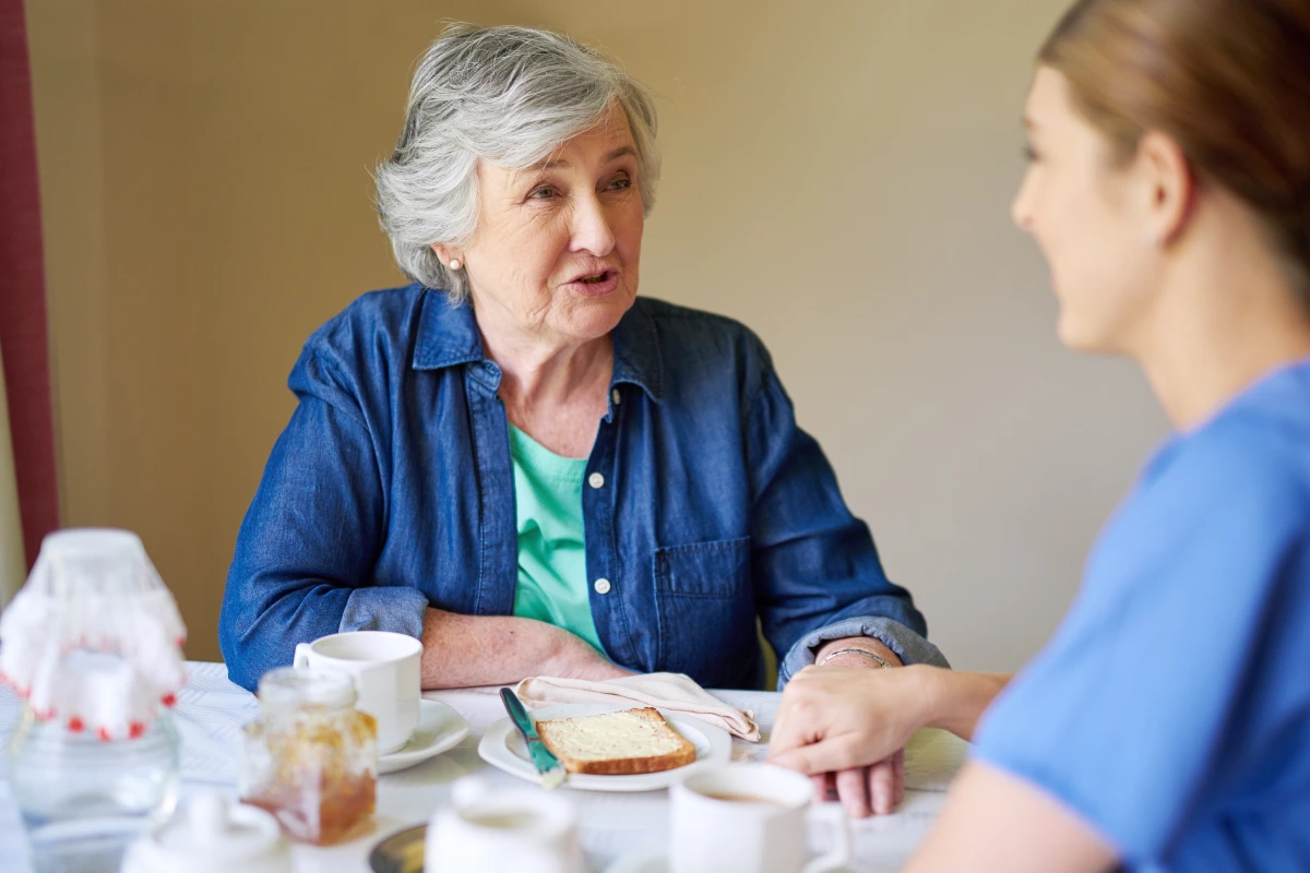 Senior woman eating with caregiver